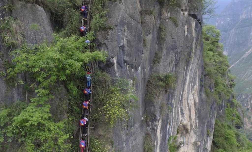 In this Saturday, May 14, 2016 photo, children wearing their school backpacks climb on a cliff on their way home from school in Zhaojue county, southwest China's Sichuan province. A village in China's mountainous west where schoolchildren must climb an 800-meter (2,625-foot)-high bamboo ladder secured to a sheer cliff face may get a set of steel stairs to improve it's safety. (Chinatopix via AP) CHINA OUT [CopyrightNotice: Chinatopix]